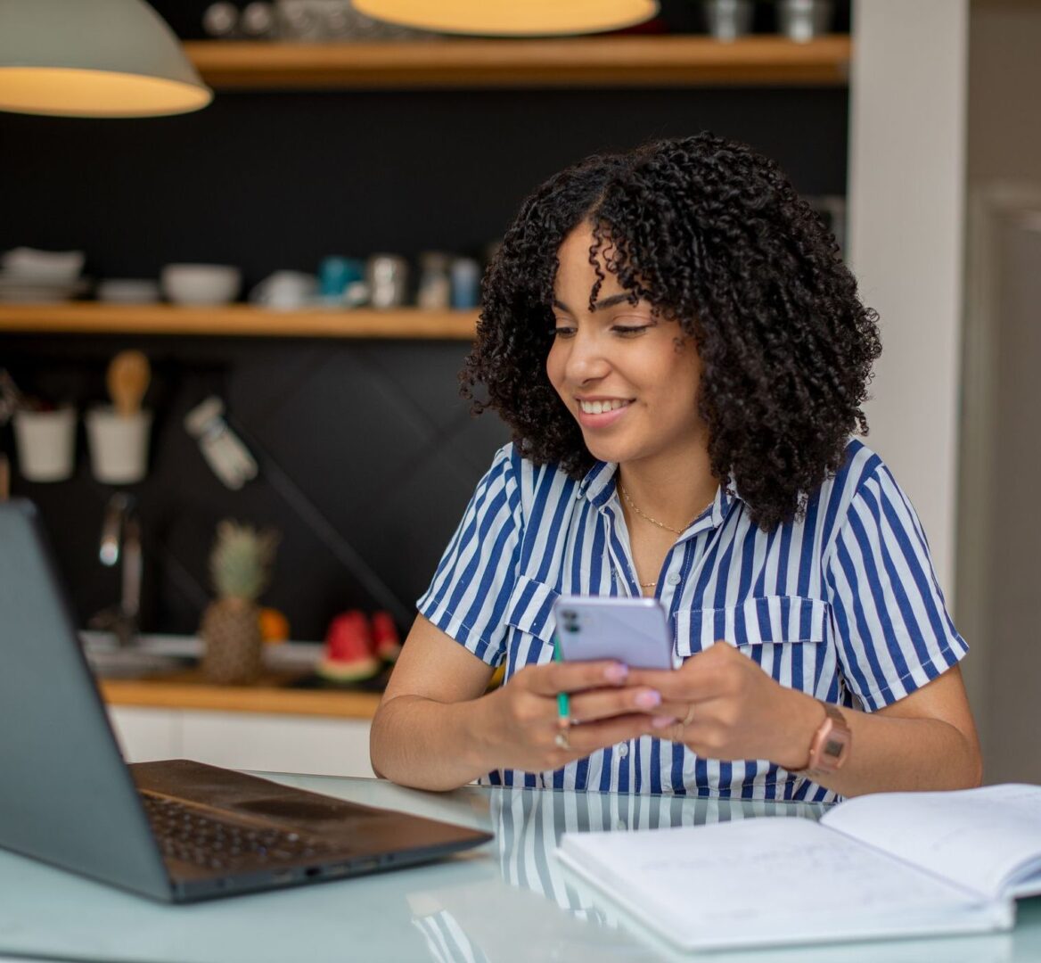 Woman smiling while using smartphone at desk.