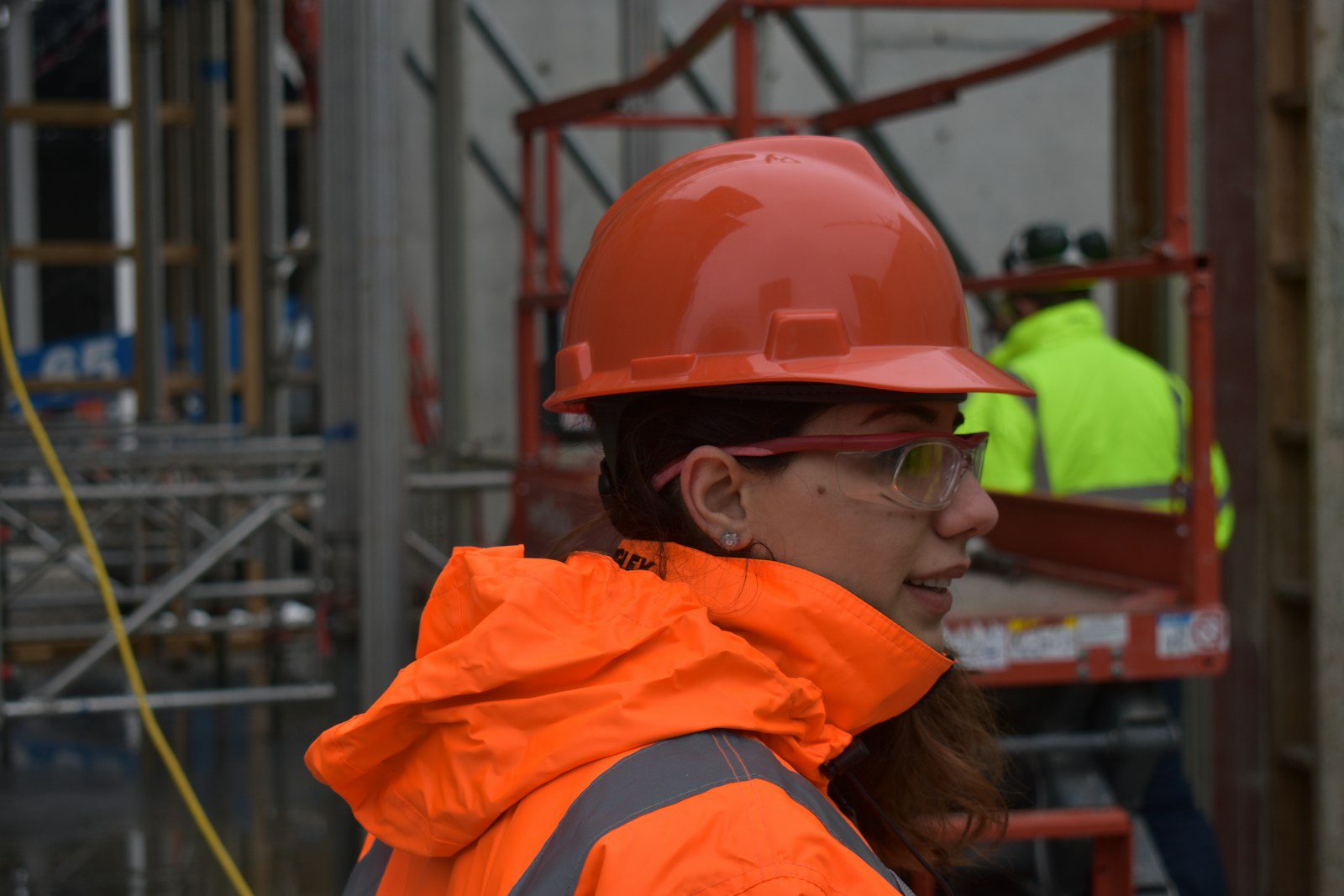 Photo by Ascel Kadhem woman wearing red hard hat and orange reflectorized jacket