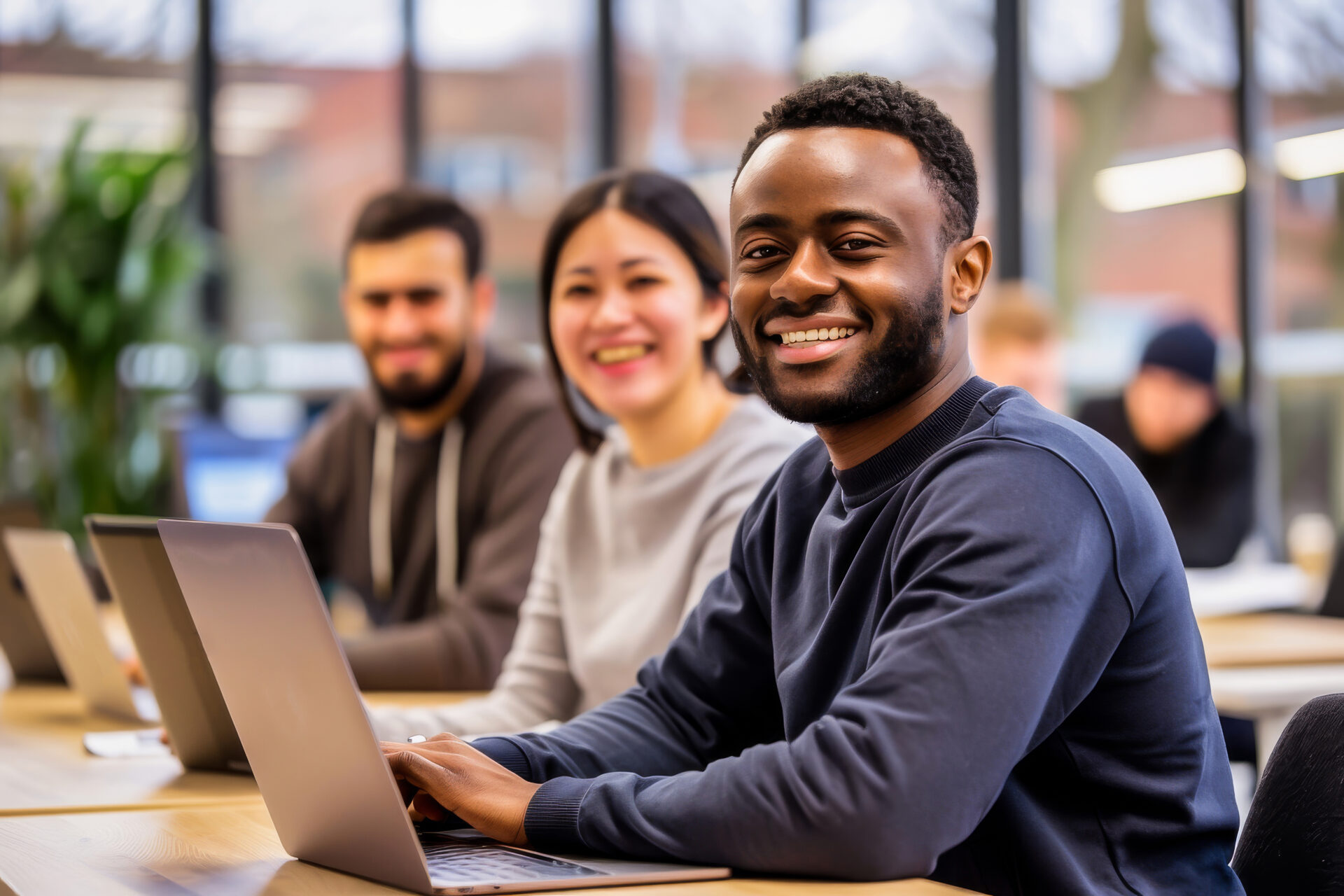 A group of diverse young professionals collaborating and smiling in a modern office environment with laptops. Perfect for business, teamwork, and corporate themes. DiverseNote Mobility. Accelerate Career Mobility.
